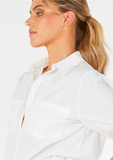 Close-up detail of the breathable vanilla cotton fabric, utility breast pocket, and functional button sleeve tab.